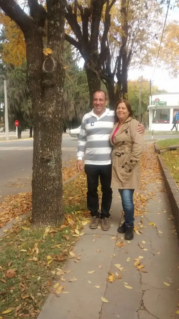 Elton e Lourdes, fundadores da Malurdes, abraçados em uma calçada arborizada